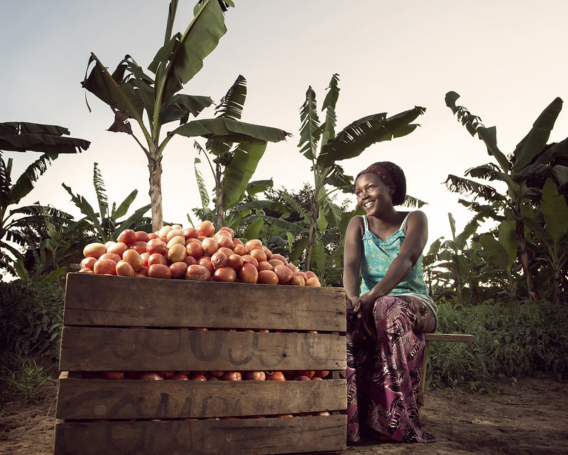 A woman farmer sits beside her harvest
