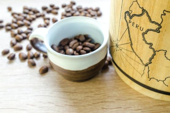 Round white and brown mug containing coffee beans