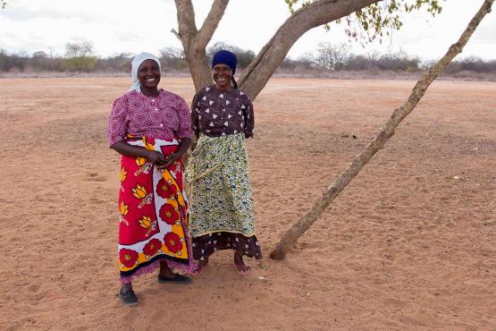 Women standing under a tree in a dry landscape